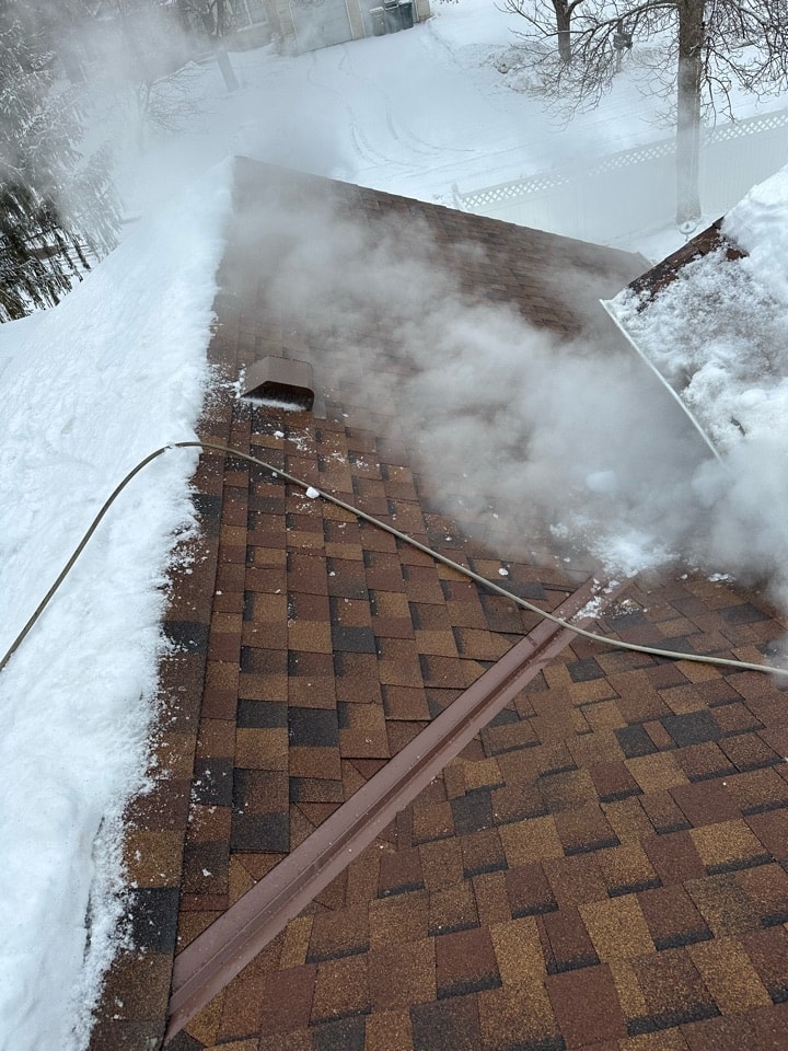 Ice dam along a shingled roof edge during steam removal by Kiser Construction in Minnesota