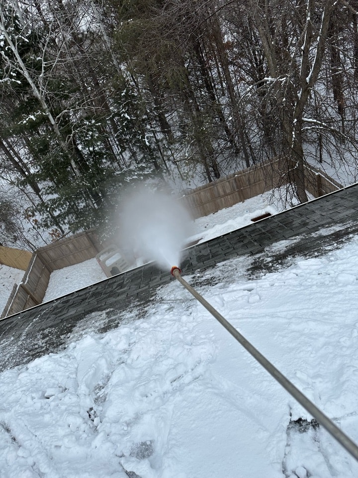 Kiser Construction crew steaming an ice dam off a roof edge in Elk River, MN
