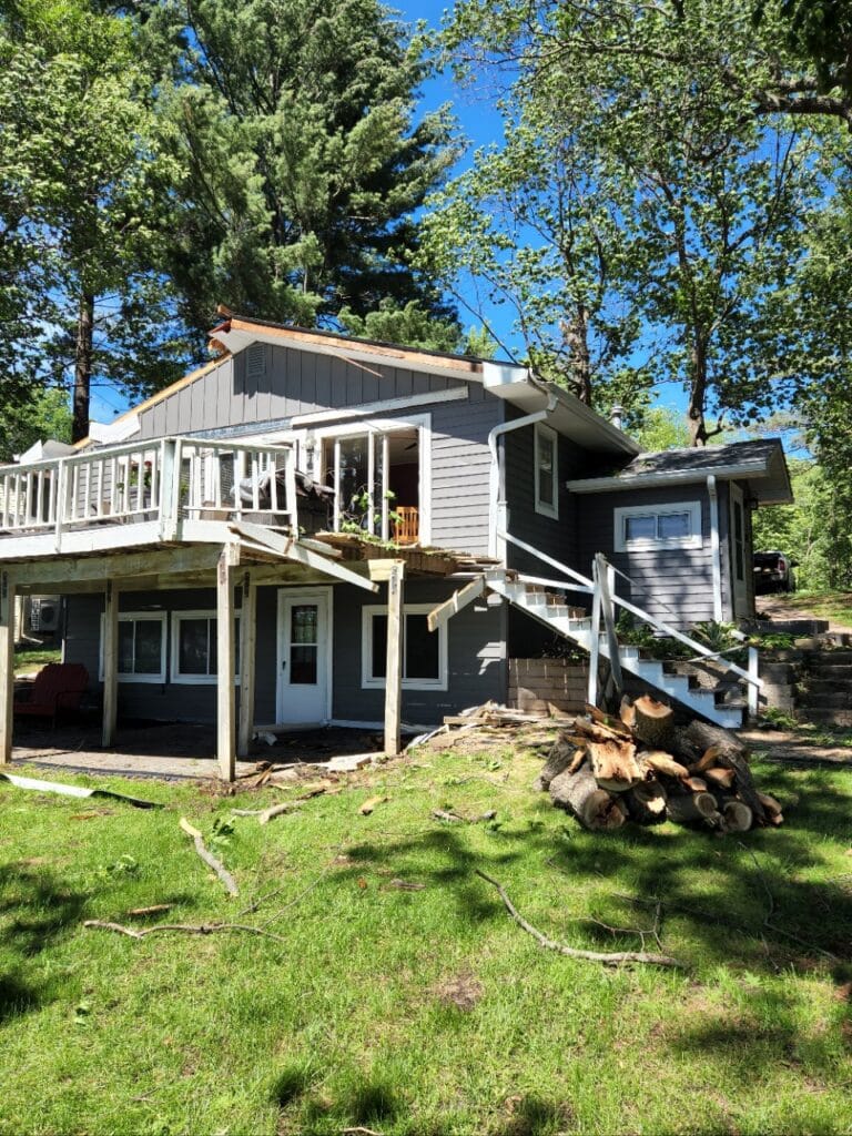Storm-damaged lake home with a fallen tree in the yard before repairs by Kiser Construction in Eden Prairie, MN