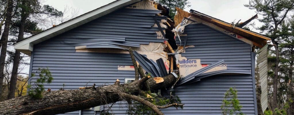Fallen tree limb on a home's roof after a wind storm in Eden Prairie, MN, repaired by Kiser Construction